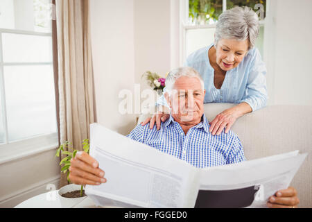 Ältere Frau im Gespräch mit älteren Mann liest Zeitung Stockfoto