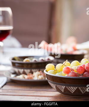 Klassische Antipasti Essen typisch für den Mittelmeerraum einschließlich Trauben, Oliven, Wein, Salami im flachen Fokus Stockfoto