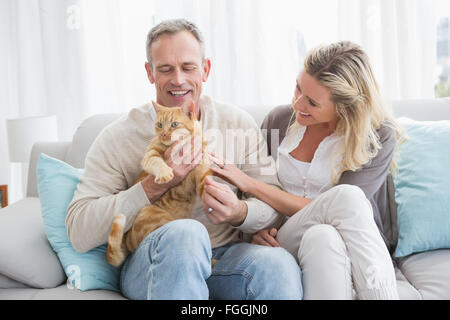 Lächelnde paar streicheln ihre Gringer Katze auf der couch Stockfoto