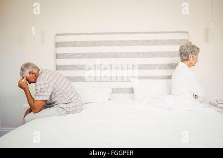 Senior paar sitzt an den gegenüberliegenden Enden des Bettes verärgert Stockfoto