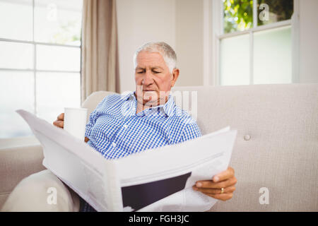 Ältere Mann liest Zeitung im Wohnzimmer Stockfoto