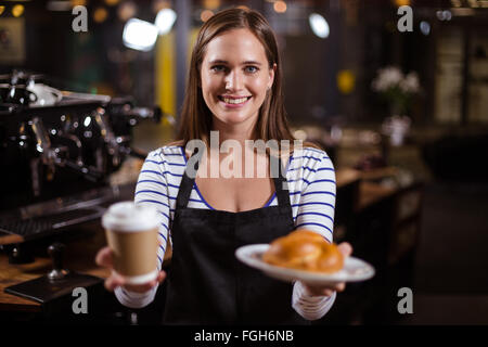 Hübsche Barista hält Einweg-Becher und brioche Stockfoto