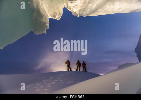 Ein Mann steht am Eingang von einer Eishöhle bei einem Winter-Besuch in die Antarktis. Stockfoto