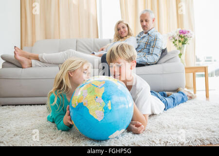 Geschwister, die Kugel auf dem Boden betrachten Stockfoto