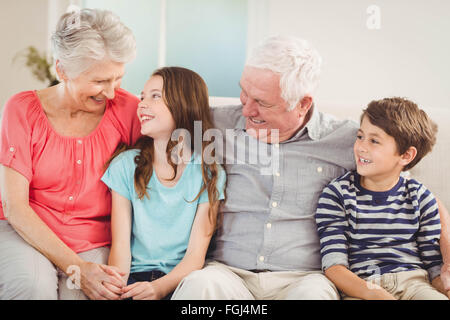 Großeltern und Enkel sitzen zusammen auf sofa Stockfoto