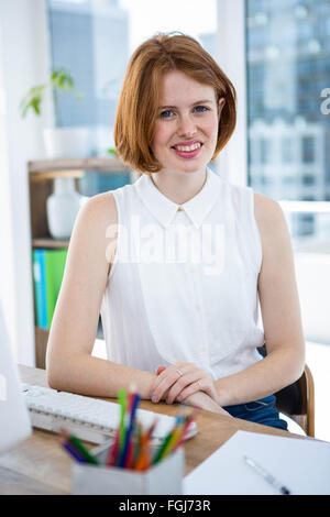 lächelnde Hipster-Business-Frau mit den Händen auf dem Schreibtisch Stockfoto