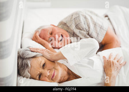 Ältere Frau für ihre Ohren während Mann Schnarchen Stockfoto