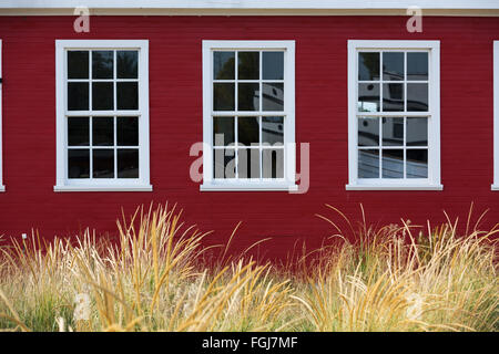 Weißes Cape Cod Windows auf roten Gebäude mit Dünengras an Glen Haven Michigan Stockfoto