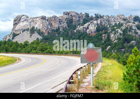 Autobahn, die zum Mount Rushmore mit einem Schild gewidmet Gutzon Borglum im Vordergrund Stockfoto