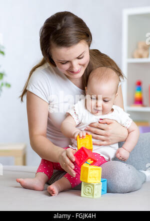 Mutter und Baby Mädchen spielen mit Entwicklungsstörungen Spielzeug im Wohnzimmer Stockfoto