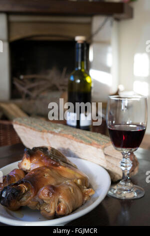 rund um den Kamin mit Rotwein und Spanferkel Essen Stockfoto