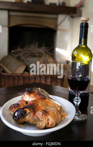 rund um den Kamin mit Rotwein und Spanferkel Essen Stockfoto