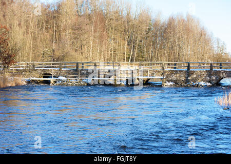 Detail der Blidingsholm Stein Bogen, dass Kreuze Brücke den Fluss Morrumsan. Dünne Schicht Schnee bedeckt den Boden und Steinen. Woode Stockfoto