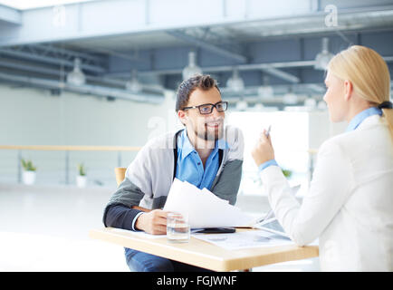 Zwei Mitarbeiter diskutieren, Pläne und Unterlagen der Tagung Stockfoto