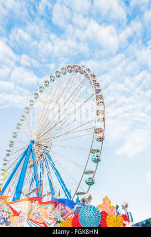 bunte Leuchtreklamen und Riesenrad auf Reisen Kirmes Stockfoto