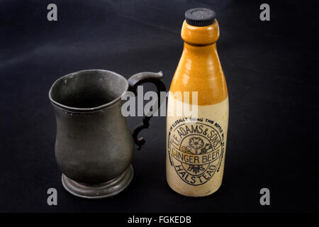 Antike steinzeug Ingwer Bier Flasche und einen George IV Zinn ein Pint Bier Becher auf schwarzem Hintergrund Stockfoto