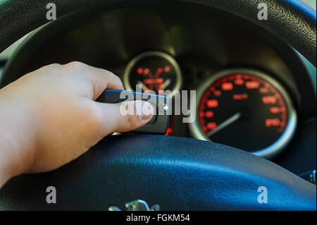 Hand des Mannes-Fahrer Auto-Taste gedrückt halten. Orange glühende Meter mit einem roten Zeiger. Kraftstoff, Drehzahlmesser, Kilometerzähler und Geschwindigkeitsmesser. Stockfoto