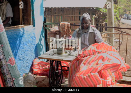 DEGAN, Äthiopien-März 25, 2013: Lokale Taylor arbeitet bei seinem Haus Veranda neben der Straße mit einer alten Nähmaschine. Stockfoto