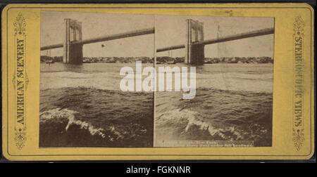 Diese stereoskopische Fotografie, die Teil der Robert N. Dennis-Sammlung ist, zeigt die Brooklyn Bridge von einer Fähre aus gesehen. Das Bild zeigt die beeindruckende Architektur der Brücke und ihre Rolle bei der Verbindung von Manhattan mit Brooklyn, einem wichtigen Teil der New Yorker Infrastruktur. Stockfoto