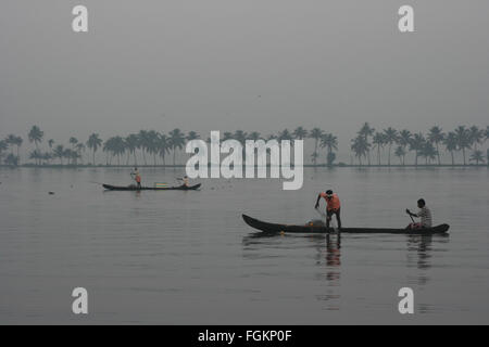 Fischer Fischer auf langen Boote Angeln in der Dämmerung Kerala Backwaters mit einer Linie der Palmen am Horizont, Indien Stockfoto