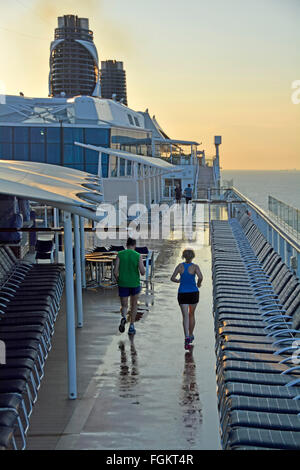 Cruise Liner Schiffsplattform am frühen Morgen Jogger läuft mit entlang Stromkreis zwischen Sonnenliegen nach über Nacht Regen im Mittelmeer zu kümmern Stockfoto