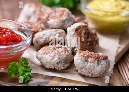 Kleine hausgemachte Frikadellen (Tiefenschärfe) auf einem alten Holztisch Stockfoto