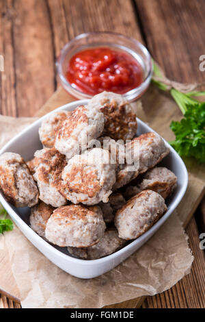 Kleine hausgemachte Frikadellen (Tiefenschärfe) auf einem alten Holztisch Stockfoto