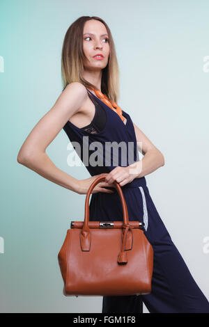 Elegante modische Frau mit Handtasche aus Leder. Stilvolle Mädchen auf grün braune Tasche halten. Frauen Mode Mode. Studio. Stockfoto