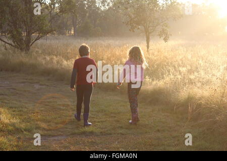 Junge Mädchen und Jungen zu Fuß entlang eines Land-Weges in der frühen Morgensonne Stockfoto