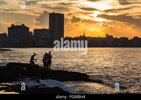 Eine kleine Gruppe von Fischer stehen auf den Felsen am Rand des Malecon in Havanna. Stockfoto