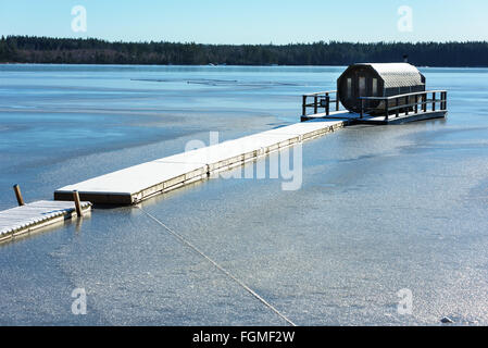 Ryd, Schweden - 16. Februar 2016: Ein achteckiger Gartenmöbel Sauna schwimmt auf einem zugefrorenen Fluss im Winter. Einzigartiges Design in einem u Stockfoto