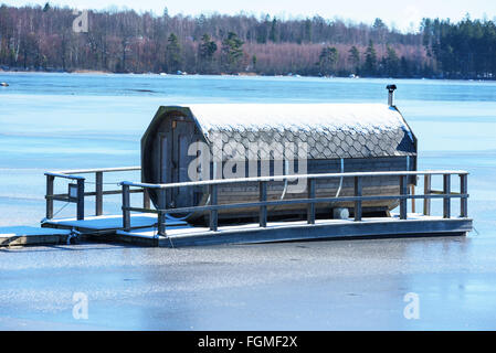 Ryd, Schweden - 16. Februar 2016: Ein achteckiger Gartenmöbel Sauna schwimmt auf einem zugefrorenen Fluss im Winter. Einzigartiges Design in einem u Stockfoto