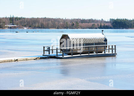 Ryd, Schweden - 16. Februar 2016: Ein achteckiger Gartenmöbel Sauna schwimmt auf einem zugefrorenen Fluss im Winter. Einzigartiges Design in einem u Stockfoto