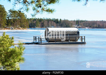 Ryd, Schweden - 16. Februar 2016: Ein achteckiger Gartenmöbel Sauna schwimmt auf einem zugefrorenen Fluss im Winter. Einzigartiges Design in einem u Stockfoto