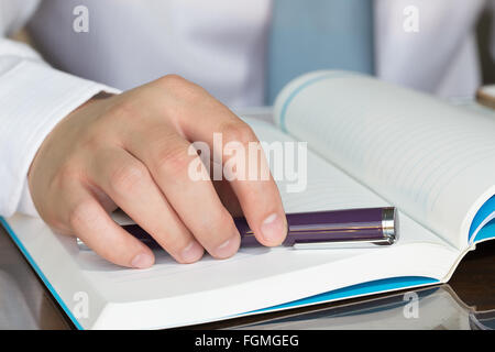 Geschäftsmann Hand mit Stift auf Notizbuch Stockfoto