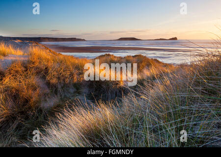 Sonnenuntergang über Würmer Kopf und Rhossili Strand angesehen von den Sanddünen von Llangennith Stockfoto