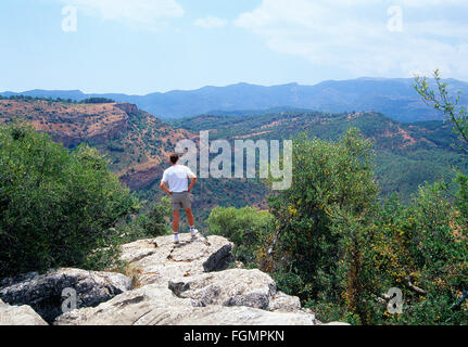 Mann auf einem Felsen, beobachtet die Landschaft. Sierra de Las Nieves Naturpark, Provinz Malaga, Andalusien, Spanien. Stockfoto