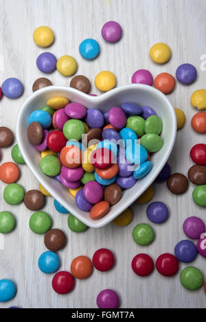 Bunten Schokoladen Smarties in einem herzförmigen weißen Teller, Schüssel Stockfoto