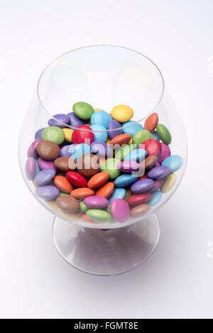 Schnaps Glas voll von bunten Schokoladen Smarties Stockfoto