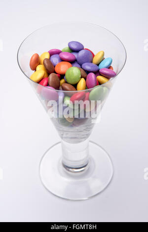 Weinglas voll von bunten Schokoladen Smarties Stockfoto