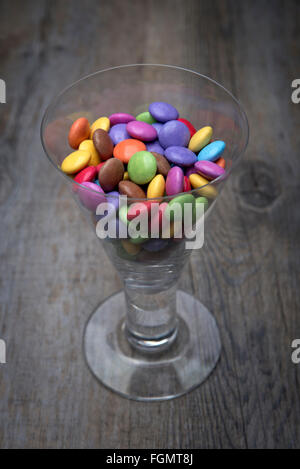 Weinglas voll von bunten Schokoladen Smarties Stockfoto