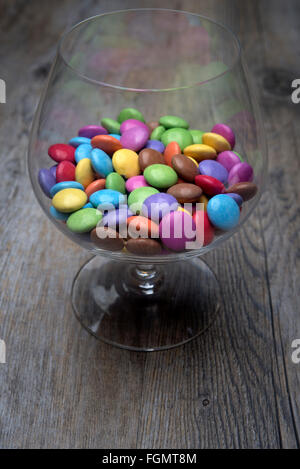 Schnaps Glas voll von bunten Schokoladen Smarties Stockfoto