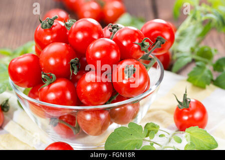 Frische Tomaten mit Blättern auf hölzernen Hintergrund Stockfoto