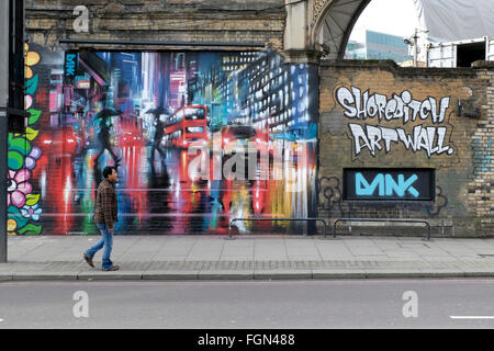 Ein Mann geht vorbei an einem Gemälde an der Wand in Shoreditch Stockfoto