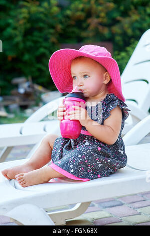 Kleines Mädchen im Herbst Park trinkt aus rosa Kunststoff-Flasche Stockfoto