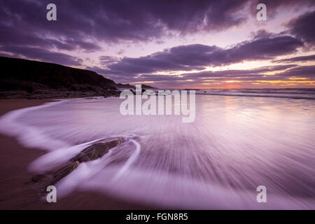 Sonnenuntergang am Welcombe Mund Beach in North Devon, UK. Eine Welle ist Rauschen über die unberührten Sand und Felsen mit Blick auf die Küste. Stockfoto