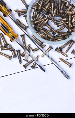 Box mit Messingschrauben und Schraubendreher auf Holztisch Stockfoto