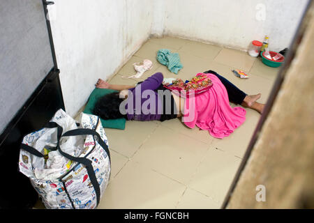 Eine Frau ist auf einer Etage ohnmächtig nach dem Genuss von zu viel Alkohol in einem Zimmer in einem Slum in Kampong Cham, Kambodscha. Stockfoto