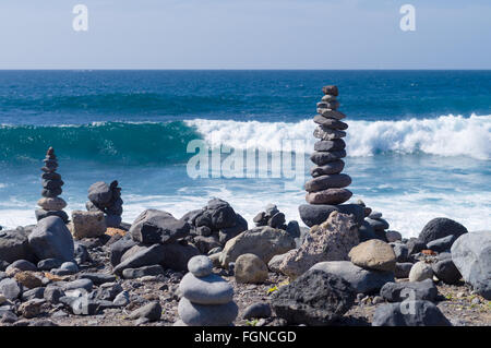 Cairn auf der steinigen Küste gegen Ozeanwelle Stockfoto