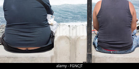 Zwei Männer, eine übergewichtige mit Blick auf das Meer des Erbauers-Hintern Stockfoto